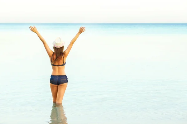 Mujer en sombrero de sol y bikini disfrutando de la vista de la playa en su —  Fotos de Stock