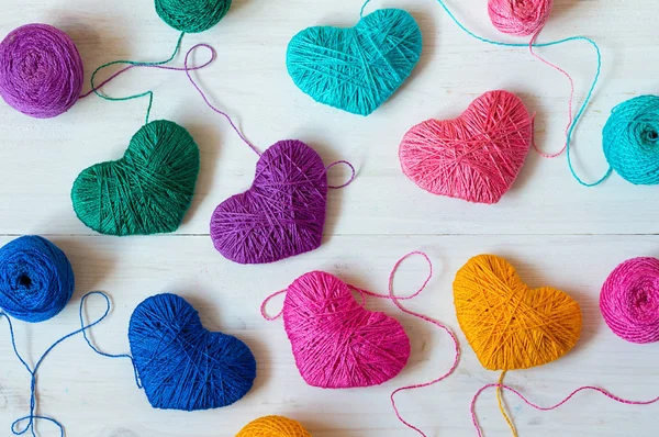 Multicolored Hearts with a balls of thread on white wooden background — Stock Photo, Image