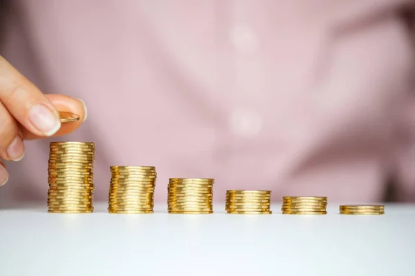 Female hand stacking gold coins into increasing columns — Stock Photo, Image