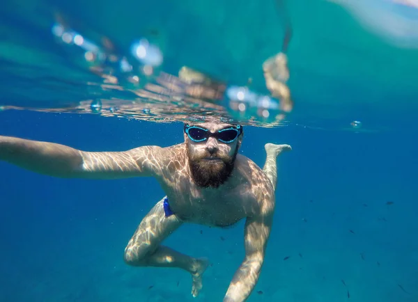 Человек делает подводное селфи с селфи палкой в синем море — стоковое фото
