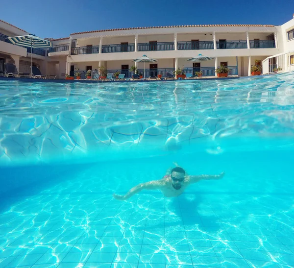 Barba joven hombre con gafas nadando bajo el agua en la piscina — Foto de Stock