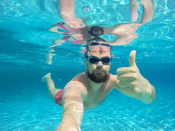 Pria berjenggot dengan kacamata menyelam di air bersih biru dengan jempol u — Stok Foto