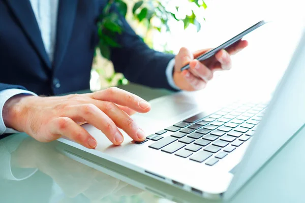 Men office worker typing on the keyboard and using smartphone — Stock Photo, Image