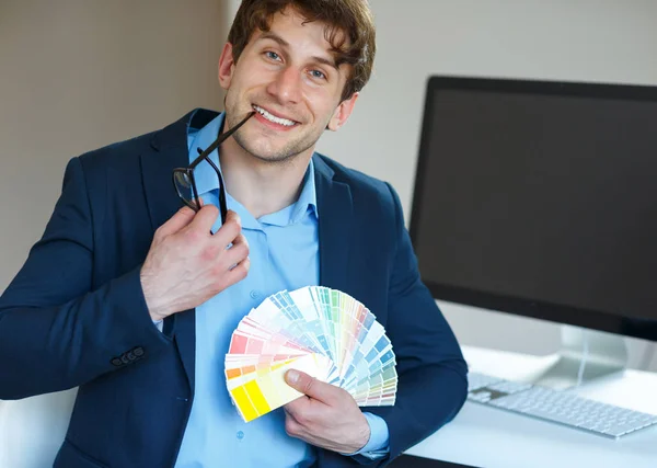 Muž hledá barevný nátěr palety na domácí kanceláři — Stock fotografie