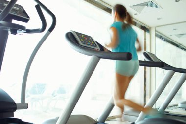 spor salonunda koşu bandı üzerinde çalışan kadın