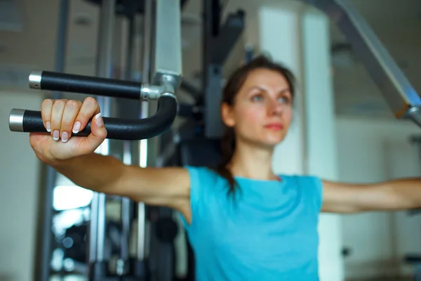 Athletic woman works out on training apparatus in gym — Stock Photo, Image