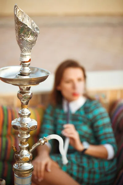 Mulher bonita fuma um narguilé em um café — Fotografia de Stock