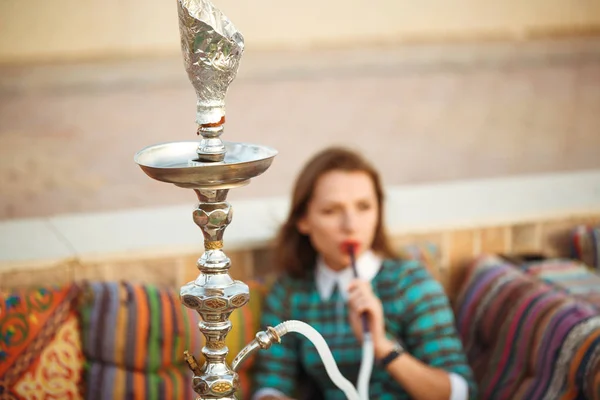 Mulher bonita fuma um narguilé em um café — Fotografia de Stock