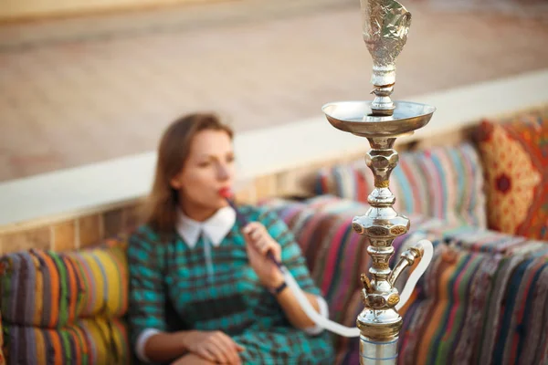 Mulher bonita fuma um narguilé em um café — Fotografia de Stock