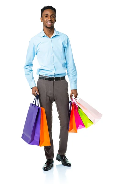 Feliz afroamericano hombre sosteniendo bolsas de compras en blanco backgr —  Fotos de Stock