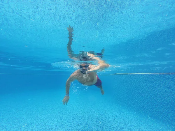 Бородач в очках плавает под водой в бассейне — стоковое фото