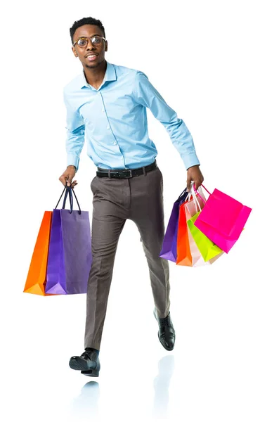 Feliz afroamericano hombre sosteniendo bolsas de compras en blanco backgr —  Fotos de Stock