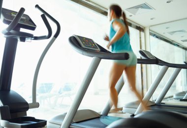 spor salonunda koşu bandı üzerinde çalışan kadın