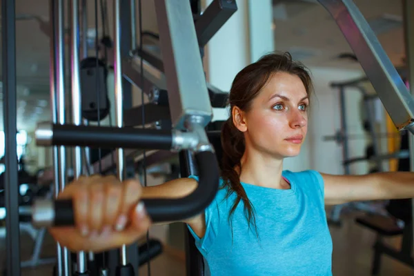 Mulher trabalha para fora no aparelho de treinamento no centro de fitness — Fotografia de Stock