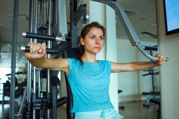 Woman works out on training apparatus in fitness center