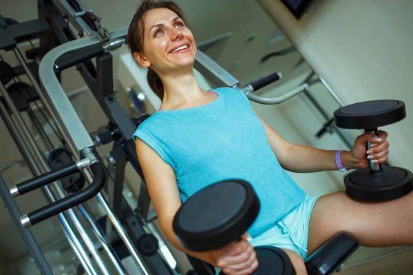 Donna con i manubri in palestra che fa esercizi sportivi — Foto Stock