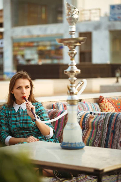 Hermosa joven fuma una cachimba en un café — Foto de Stock