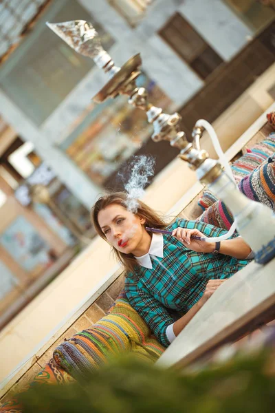 Mulher bonita fuma um narguilé em um café — Fotografia de Stock