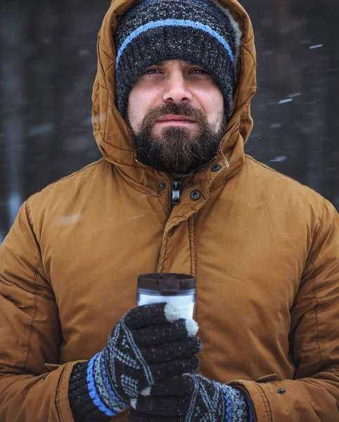 Beard man with hot drink in thermos cup in winter forest — Stock Photo, Image