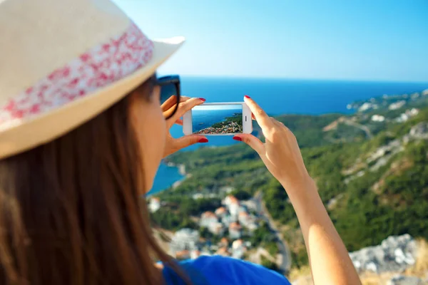 Lány kalapban fotói az Adriai-tenger azáltal, hogy a smartphone — Stock Fotó