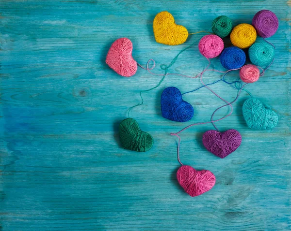 Multicolored Hearts with a balls of thread on blue wooden backgr — Stock Photo, Image
