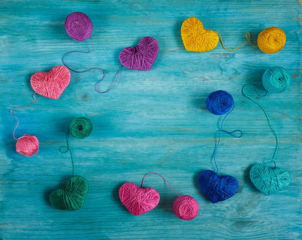 Corazones multicolores con bolas de hilo sobre fondo de madera azul — Foto de Stock