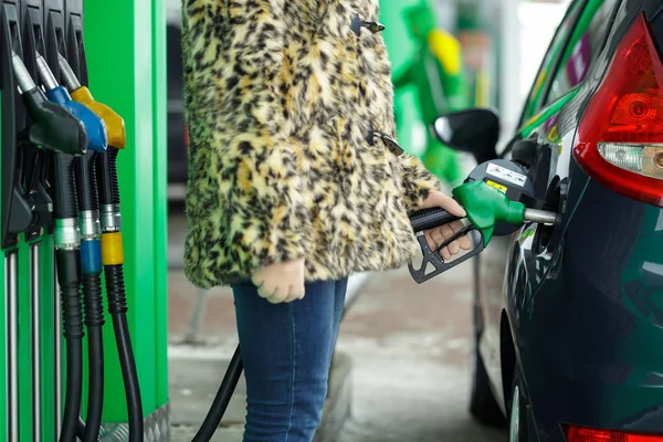 Mujer llena gasolina en su coche en una gasolinera en invierno — Foto de Stock