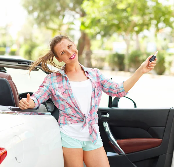 Bir üstü açık araba ile anahtar taşı elinde duran genç kadın — Stok fotoğraf