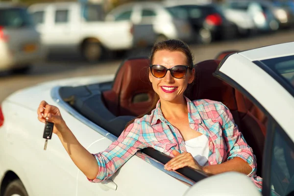 Joven mujer bonita sentada en un coche descapotable con las llaves en — Foto de Stock