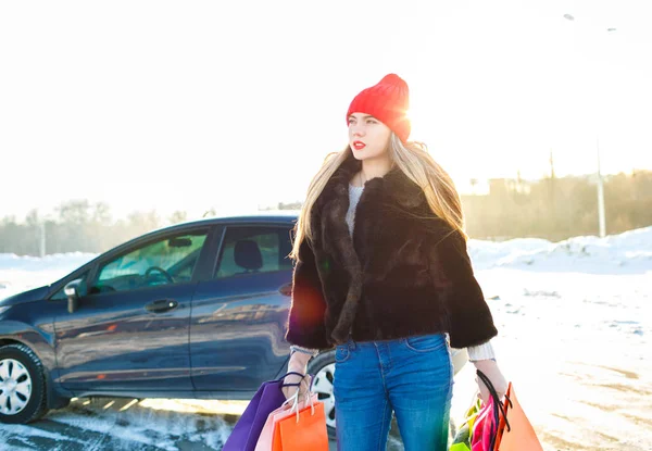 Mosolygó kaukázusi nő tartja őt bevásárló táska közelében az autó — Stock Fotó