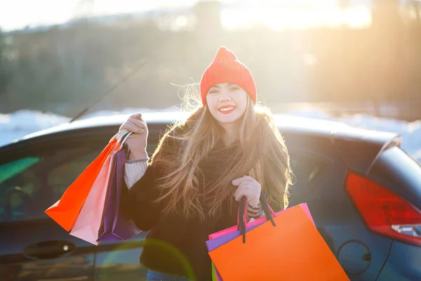 Sonriente mujer caucásica sosteniendo su bolsa de compras cerca del coche —  Fotos de Stock