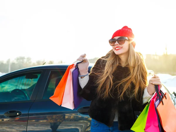 Sonriente mujer caucásica sosteniendo su bolsa de compras cerca del coche — Foto de Stock