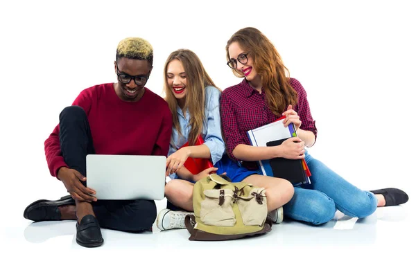 Τρεις φοιτητές χαρούμενος κάθεται με βιβλία, φορητό υπολογιστή και τσάντες — Φωτογραφία Αρχείου