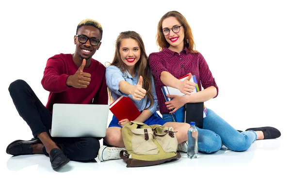 Tres estudiantes felices con libros, laptop y bolsos con pulgares arriba —  Fotos de Stock