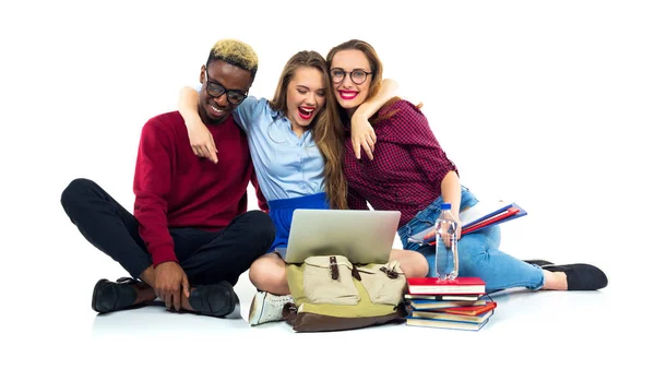 Tre studenti felici seduti con libri, laptop e borse — Foto Stock