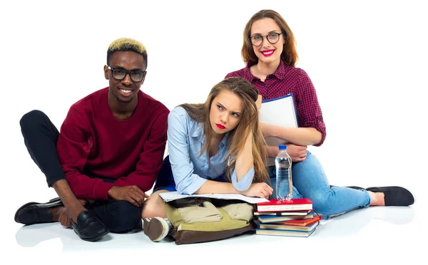 Tres estudiantes felices sentados con libros, laptop y bolsas —  Fotos de Stock