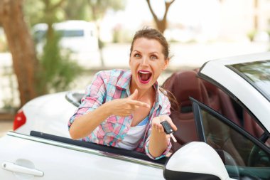 Bir üstü açık araba ile anahtar taşı elinde duran genç kadın