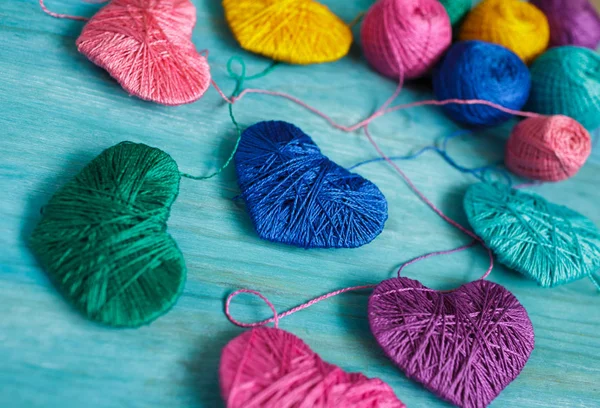 Corazones multicolores con bolas de hilo sobre fondo de madera azul — Foto de Stock