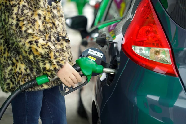 Woman fills petrol into her car at a gas station in winter