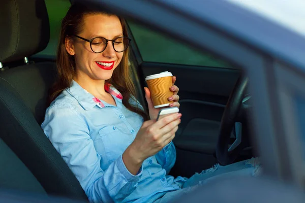 Joven empresaria enviando un mensaje de texto y bebiendo café w — Foto de Stock