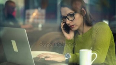 Bir kafede bir akıllı telefon konuşma ve çalışma güzel genç kadın