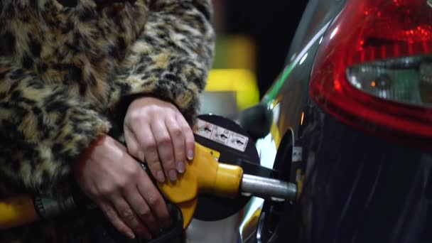 Mujer llena gasolina en su coche en una gasolinera en invierno — Vídeos de Stock