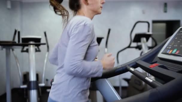 Mujer corriendo en la cinta en el gimnasio — Vídeos de Stock