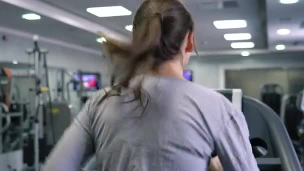 Nő fut a futópadon a tornateremben — Stock videók