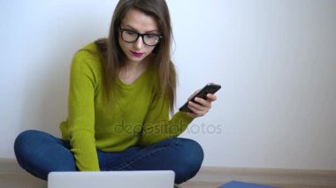 Laptop ve evde katta oturan smartphone kullanan güzel kız