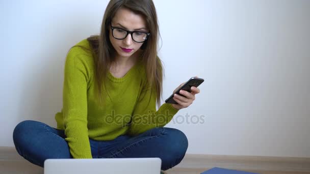 Menina bonita usando laptop e smartphone sentado no chão em casa — Vídeo de Stock