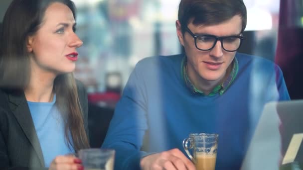 Beautiful young woman and man negotiating in a cafe — Stock Video