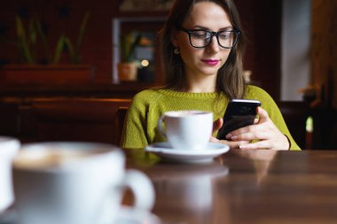 Kahve içme ve kafede smartphone kullanarak genç kadın
