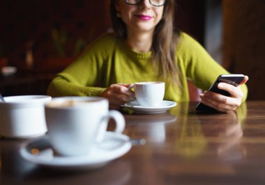 Kahve içme ve kafede smartphone kullanarak genç kadın