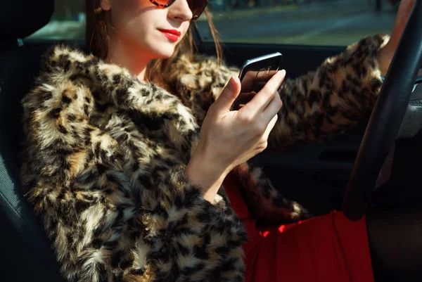 Schöne Frau im Pelzmantel mit roten Lippen mit Smartphone in — Stockfoto